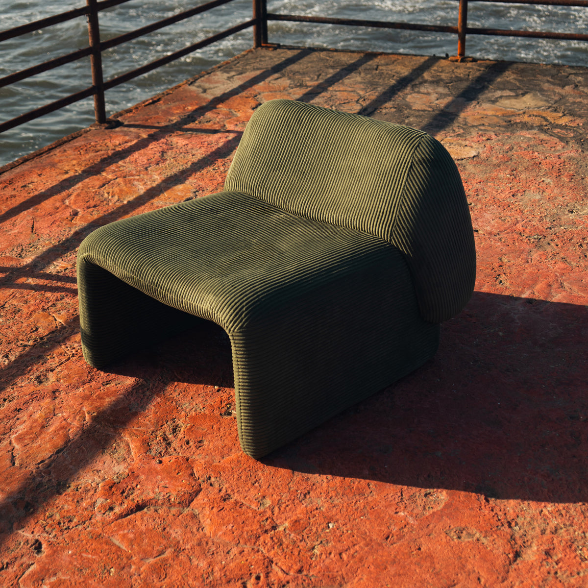 Furrow Chair in olive corduroy, armless, with closed sides that carry down to the floor.