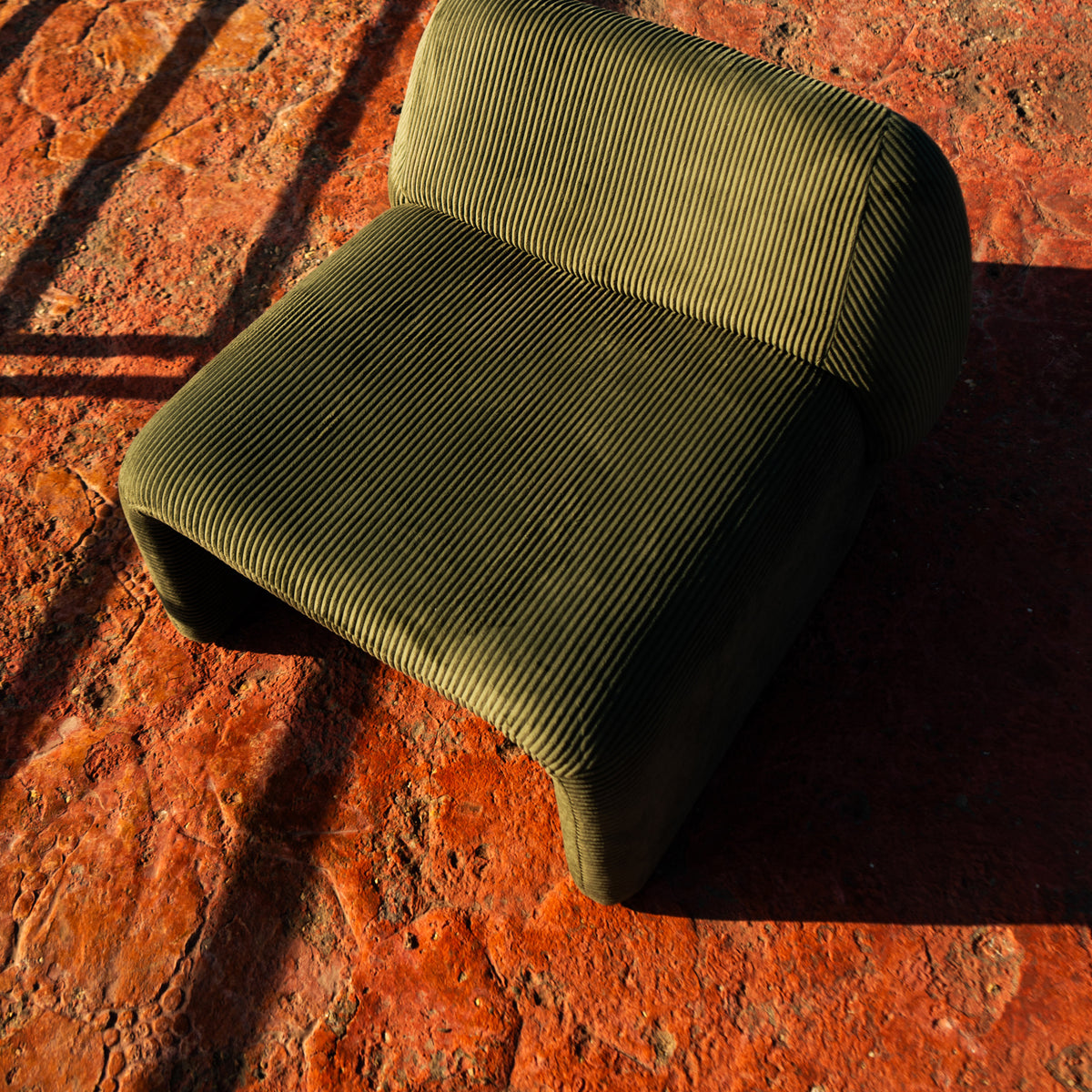 Furrow Chair at an angle, showing the low back and the rolled seat front.